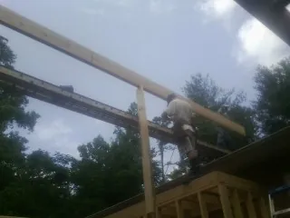 Carpenter setting a ridge beam over a new addition frame — Ice Dam Removal by Roofing Brothers in New Columbia