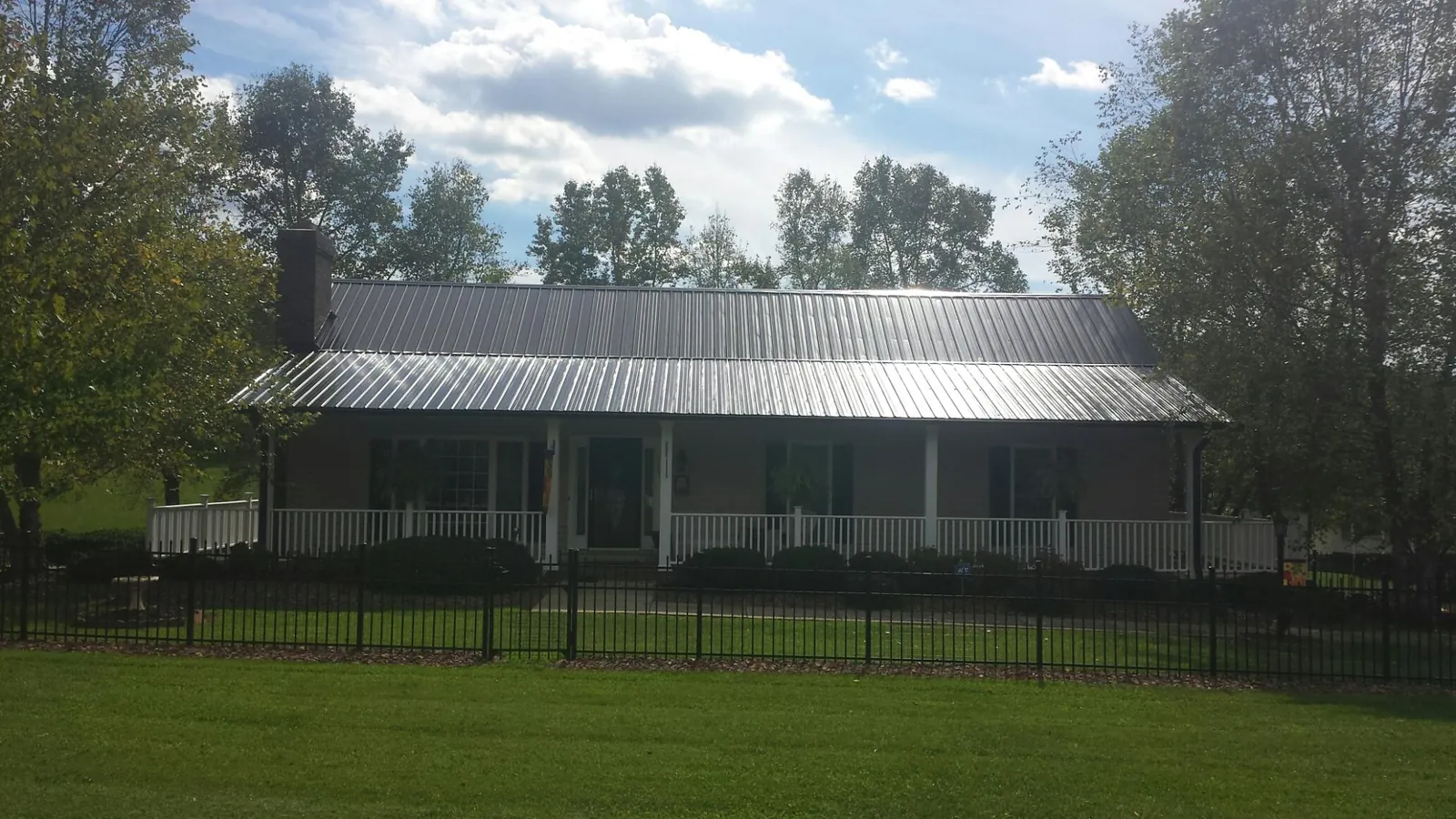 Gray metal roof on a brick ranch with a full width front porch — Gutter Guard Installation work by our crew in New Columbia