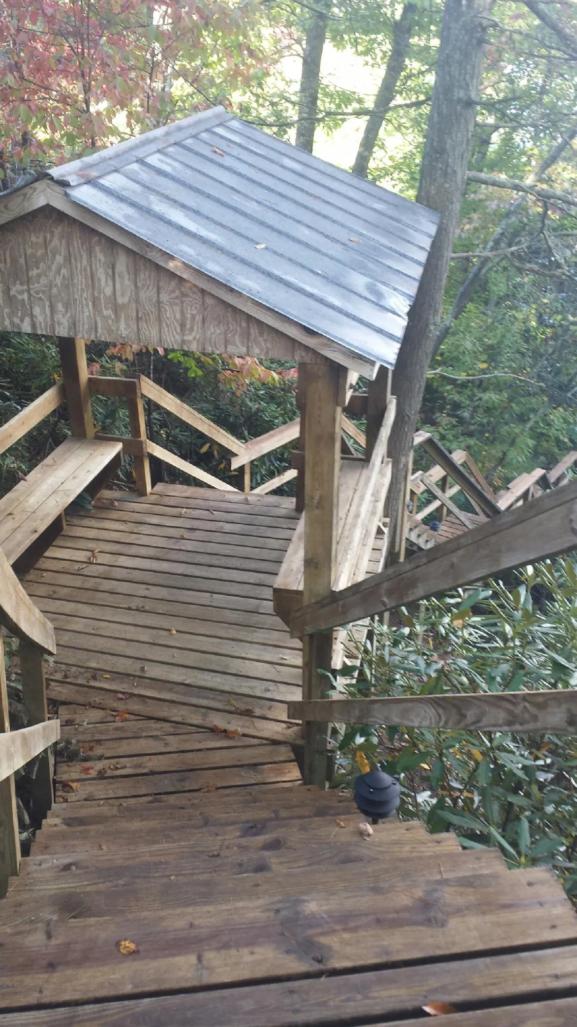 Metal roofed shelter over wooden steps on a wooded walkway — Skylight Repair & Installation work by our crew in New Columbia