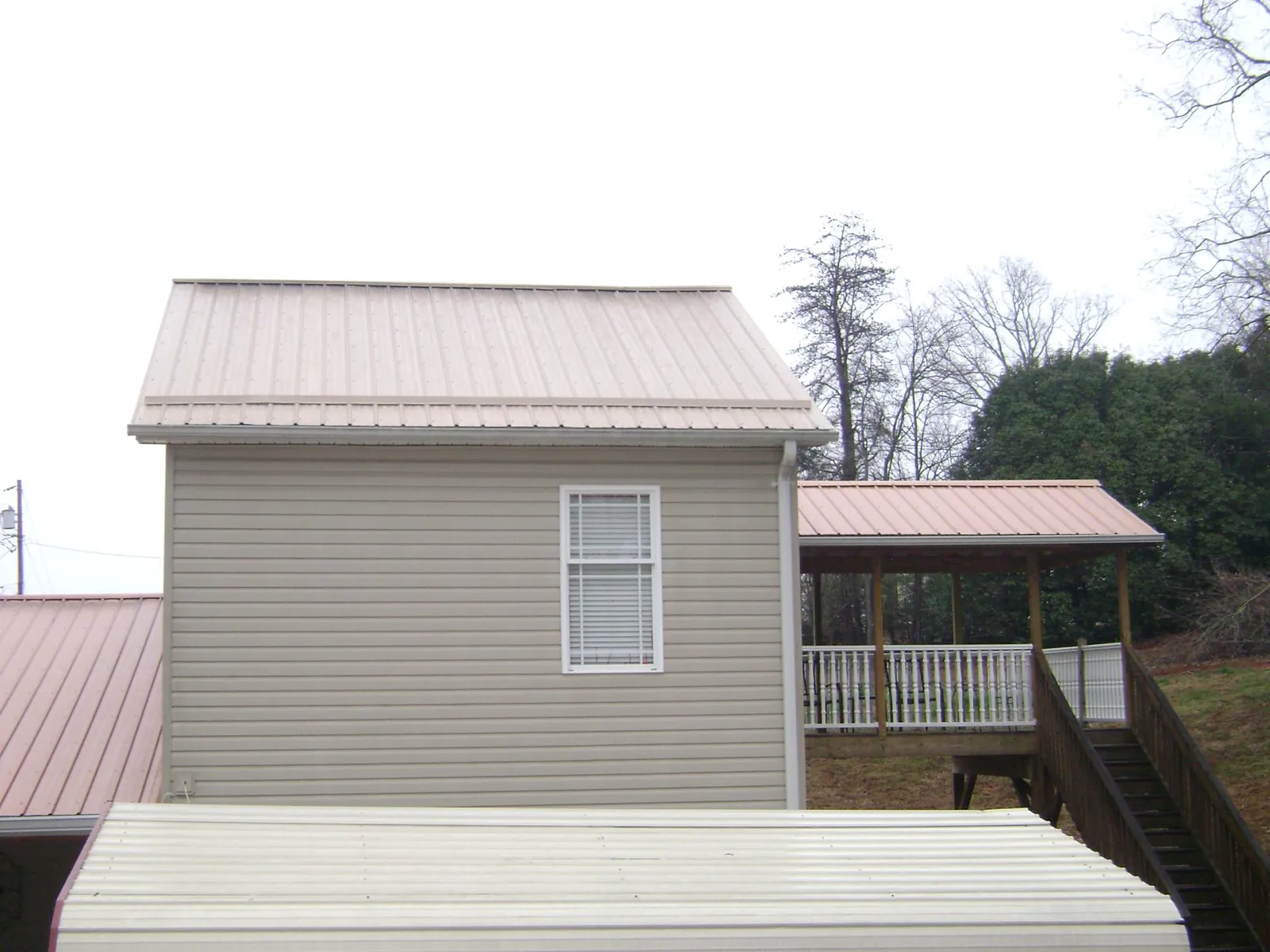 Tan metal roofs on a two story addition and attached porch, from a Roof Replacement job in New Columbia