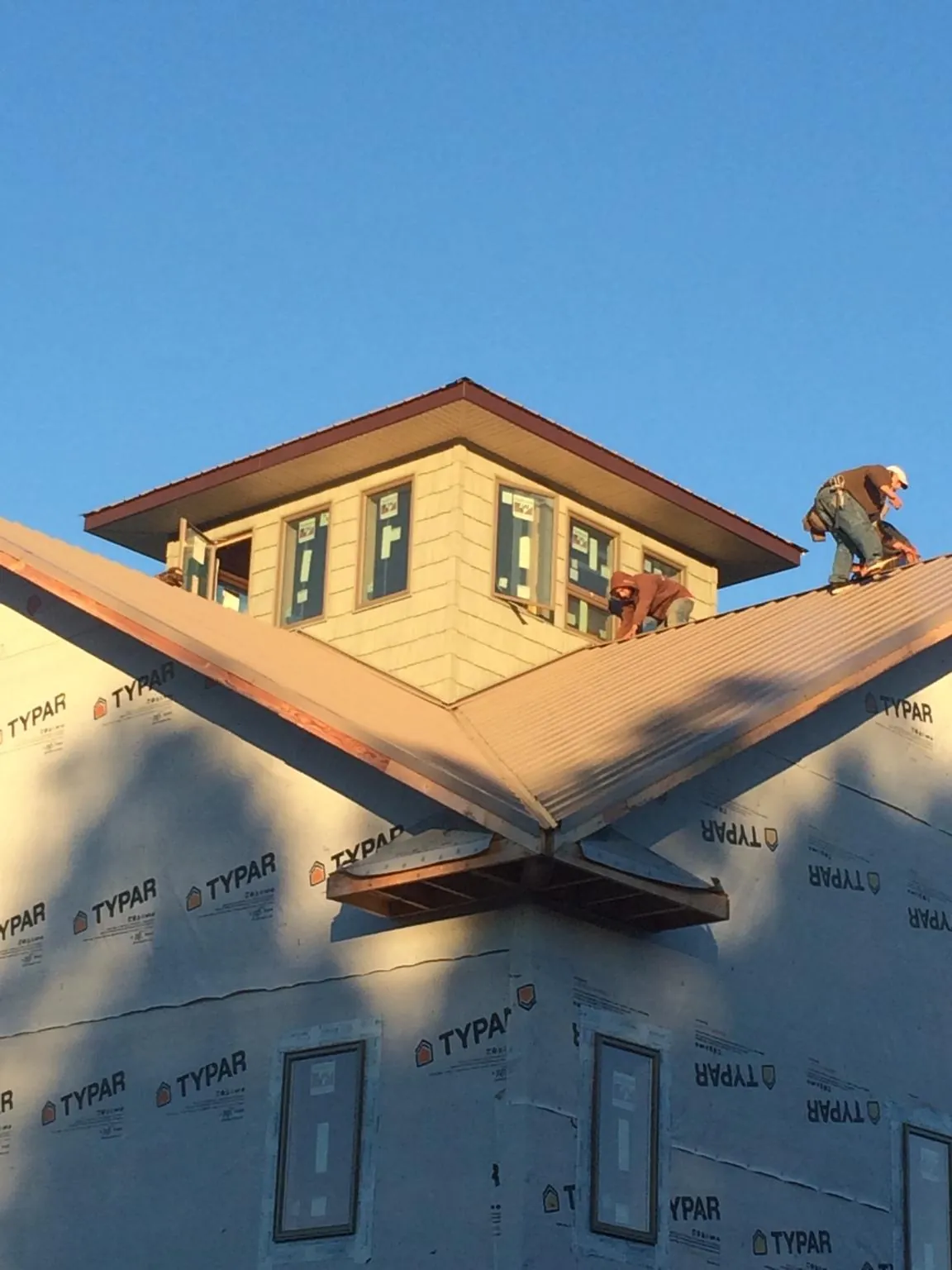 Roofers working around a rooftop cupola on a new metal roof at sunset — Roof Waterproofing in New Columbia by Roofing Brothers